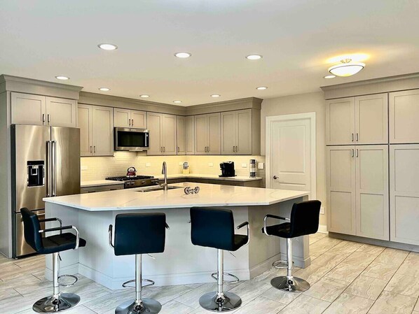 Enjoy cooking in this well-equipped kitchen with a central island, sink, and bar stools.
