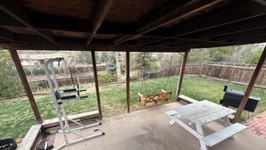 A covered patio with a concrete floor, a picnic table, a grill, and outdoor exercise equipment. - Boho 3BR, 2BA Home in Colorado Springs Sleeps 6+ (Colorado Springs)