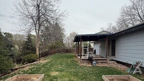 A backyard with a covered patio, a wooden deck, and a house in the background. - Boho 3BR, 2BA Home in Colorado Springs Sleeps 6+ (Colorado Springs)