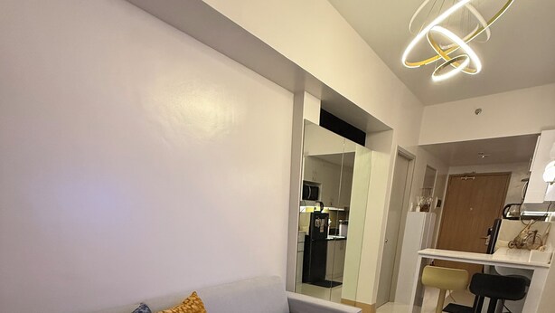A modern living room with a grey sofa, patterned cushions, a fluffy rug, and a contemporary light fixture. - Glamorous 2BR/1Bath/Wifi/Netflix/Heater/Washing/5starBnB (Pasay)