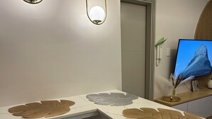 A modern kitchen with a white countertop, two bar stools, and a built-in TV. - Glamorous 2BR/1Bath/Wifi/Netflix/Heater/Washing/5starBnB (Pasay)
