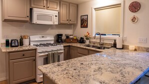 A kitchen with white cabinets, a granite countertop, a stove, a microwave, and a sink. - Wellness Retreat at Lake Cushman. Sauna, Cold Plunge, Fire Pit (Hoodsport)