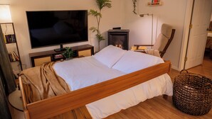 A bedroom with a wooden bed, a television, a fireplace, a bookshelf, and a plant. - Wellness Retreat at Lake Cushman. Sauna, Cold Plunge, Fire Pit (Hoodsport)