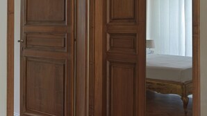 Una puerta de madera con un espejo que refleja una cama y una ventana con cortinas.