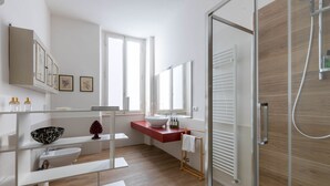 A modern bathroom with a glass shower enclosure, a white sink, and a red countertop. - Modern, Bright and Spacious 2-Bedroom Apartment (Firenze)