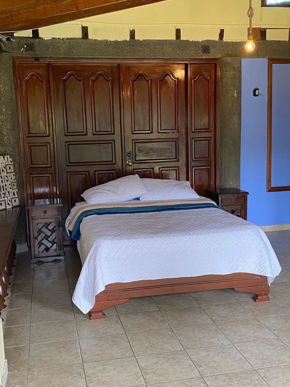 A bedroom with a large wooden bed, a nightstand, and a wardrobe.