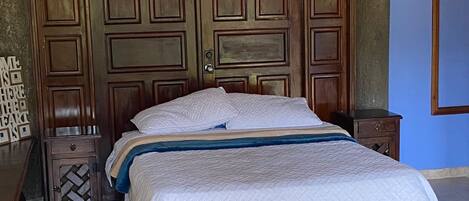 A bedroom with a large wooden bed, a nightstand, and a wardrobe.