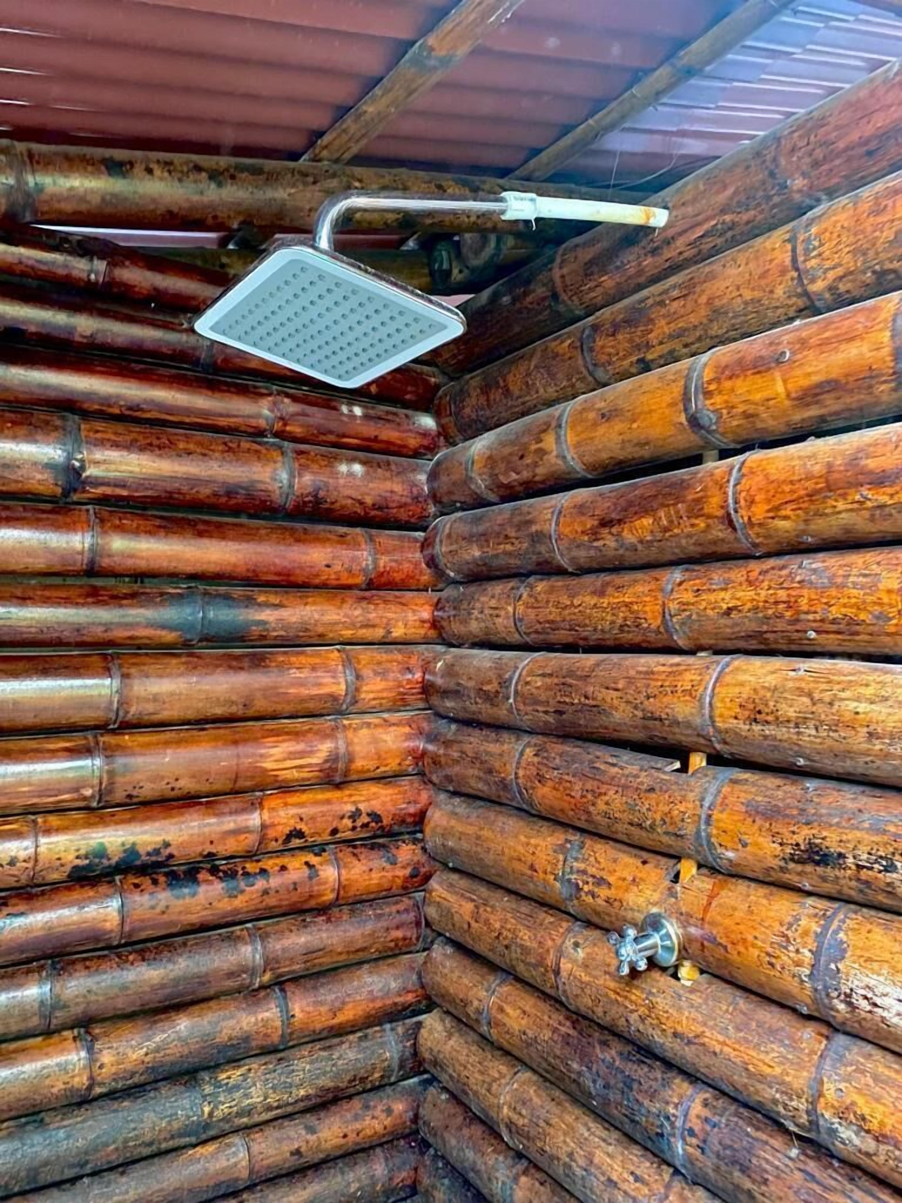 A log cabin interior with a metal showerhead mounted on the ceiling.