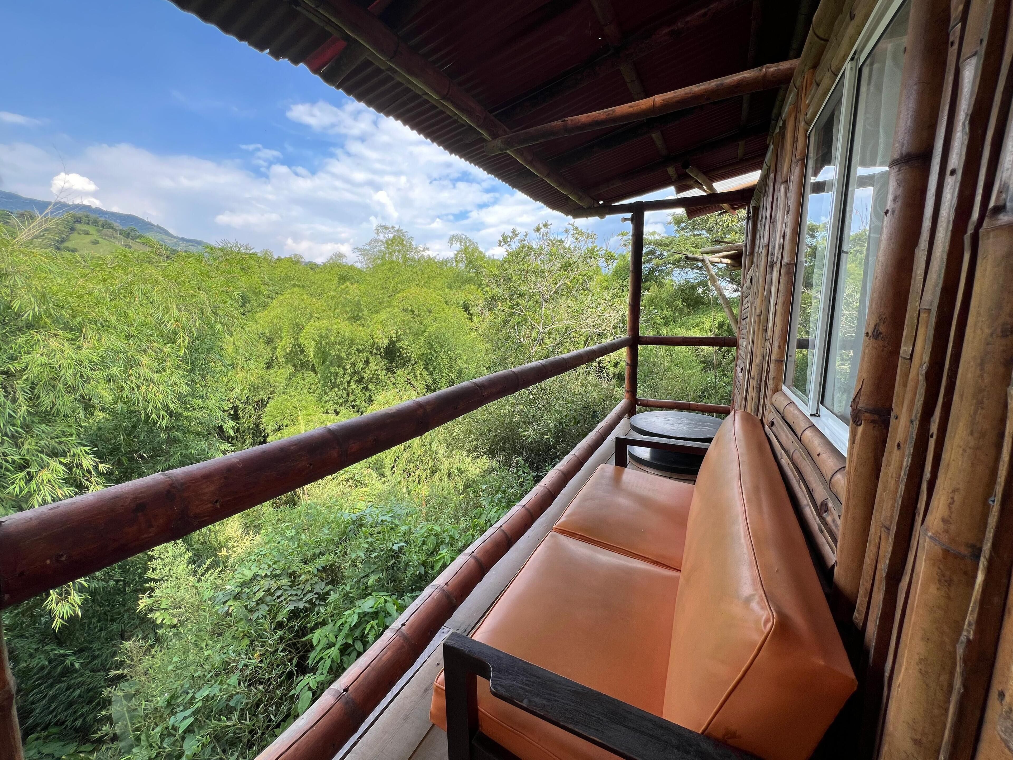 Un balcone con vista su una vegetazione lussureggiante e delle colline.