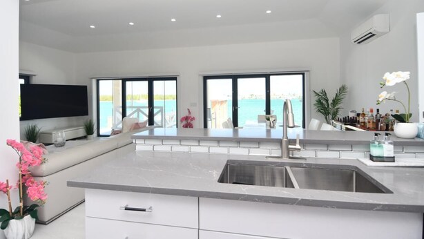 A modern kitchen with a large island, a built-in TV, and a view of the ocean.