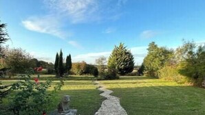 Un chemin de pierres qui traverse un jardin, avec un ciel dégagé.