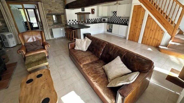 Un vaste espace de vie comprenant un canapé en cuir, une table basse en bois et une cuisine à l’arrière-plan.