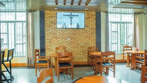 Interior de una iglesia con bancos de madera, un crucifijo en la pared y amplias ventanas con barrotes de metal.
