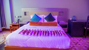 Habitación de hotel con una cama grande, dos almohadas, una mesita de noche, un escritorio y un armario.
