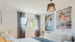 Un dormitorio con cama, cómoda, silla y carteles en la pared.