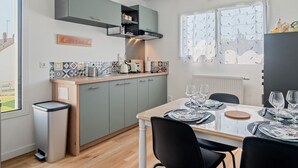 Una cocina moderna con gabinetes grises, un salpicadero de azulejos y un comedor con una mesa dispuesta para cuatro.