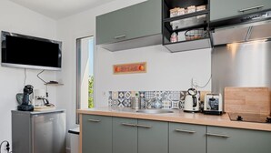 Una cocina moderna con armarios grises, un refrigerador de acero inoxidable, una cafetera y un tostador.