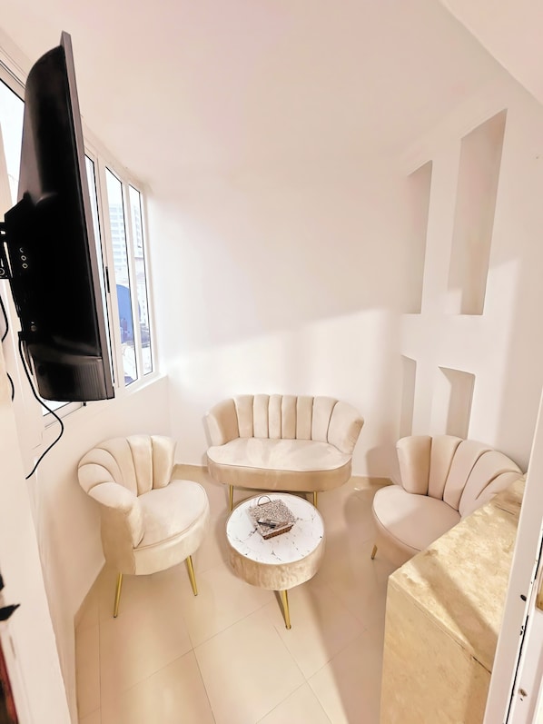 A modern living room with a sofa set, a coffee table, and a flat-screen TV mounted on the wall.