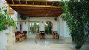 Un espacio de estar techado al aire libre con techo de madera, una mesa pequeña y mobiliario de mimbre.