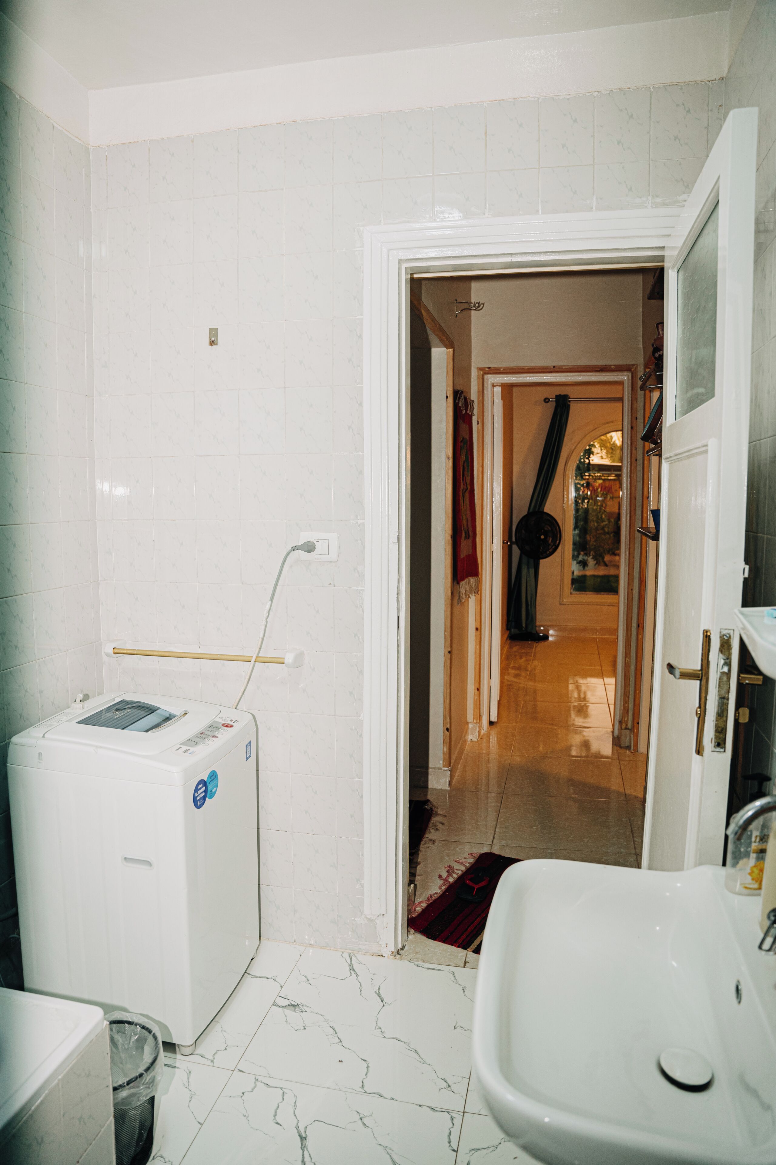 Un baño con lavamanos blanco, lavadora y zona de ducha.