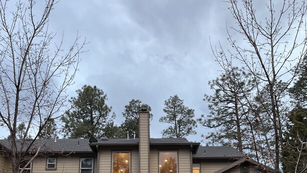 A two-story house with a covered front porch, a chimney, and a driveway leading to the entrance.