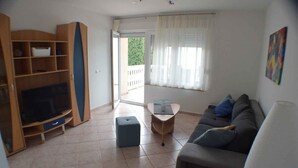 Una sala de estar con televisor, sofá, mesa de centro y estantería.