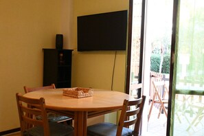 Une table ronde en bois, entourée de chaises, un téléviseur fixé au mur et un panier posé sur la table.