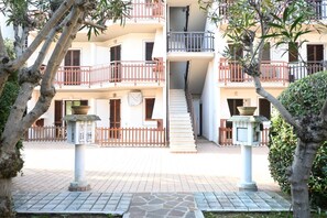 Un immeuble à plusieurs étages doté de balcons, d’un escalier et d’un système d’éclairage extérieur.