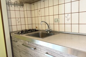A kitchen with a stainless steel sink, a gas stove, and a tiled backsplash.
