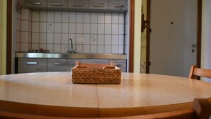 A kitchen with a tiled backsplash, a stove, and a round table with a woven basket. - M421 - Marcelli, two-room apartment with patio 100m from the sea (Marcelli)