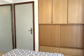 A bedroom with a bed, a wardrobe, and a door.