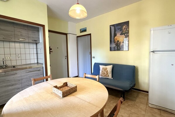 A compact living space with a kitchen, dining area, and a sofa with a cushion.