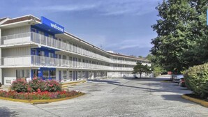 Un motel avec une enseigne « Bienvenue », de nombreux balcons et un parking.