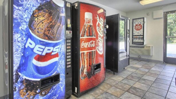 Un espace équipé de distributeurs automatiques de boissons, proposant des produits des marques Pepsi et Coca-Cola.