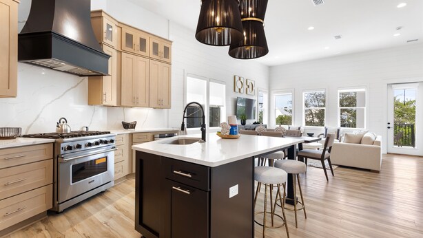 A modern kitchen with a large island, wooden cabinets, and a stainless steel stove. - Easy Street | New Home | 7 Beds | Pool | Golf Cart | Bikes (Santa Rosa Beach)