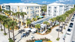 A multi-story hotel with a central courtyard, palm trees, and a sign reading "BILLPLACE." - Easy Street | New Home | 7 Beds | Pool | Golf Cart | Bikes (Santa Rosa Beach)