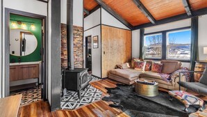 Ein modernes Interieur mit einer Steinwand, einem Kamin, einer Couch und Blick auf eine verschneite Landschaft.