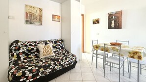 Een moderne woonkamer met een zwarte bank, een eettafel met stoelen en kunstwerken aan de muur.