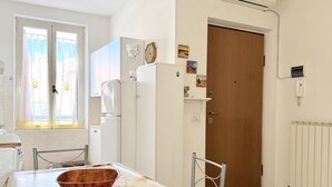 Een keuken met een eettafel, stoelen, een koelkast en een houten deur.