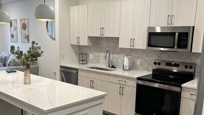 A modern kitchen with white cabinetry, stainless steel appliances, and a central island.