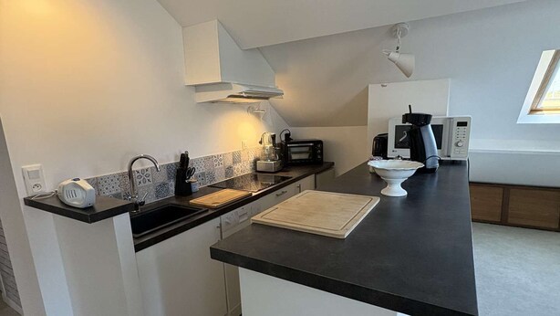 A modern kitchen with white cabinets, a black countertop, and a built-in microwave.
