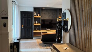 Ein modernes Wohnzimmer mit Fernseher, Sofa und Holzpaneelen.