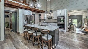 A spacious kitchen with a central island, bar stools, stainless steel appliances, and a wooden ceiling. - Toccoa Time - Riverside | Pet Friendly | Firepit | Pool table (Blue Ridge)