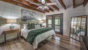 A bedroom with a bed, nightstands, a ceiling fan, a painting, and a window with blinds. - Toccoa Time - Riverside | Pet Friendly | Firepit | Pool table (Blue Ridge)