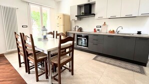 Eine moderne Küche mit Esstisch, Stühlen und einem Kühlschrank.