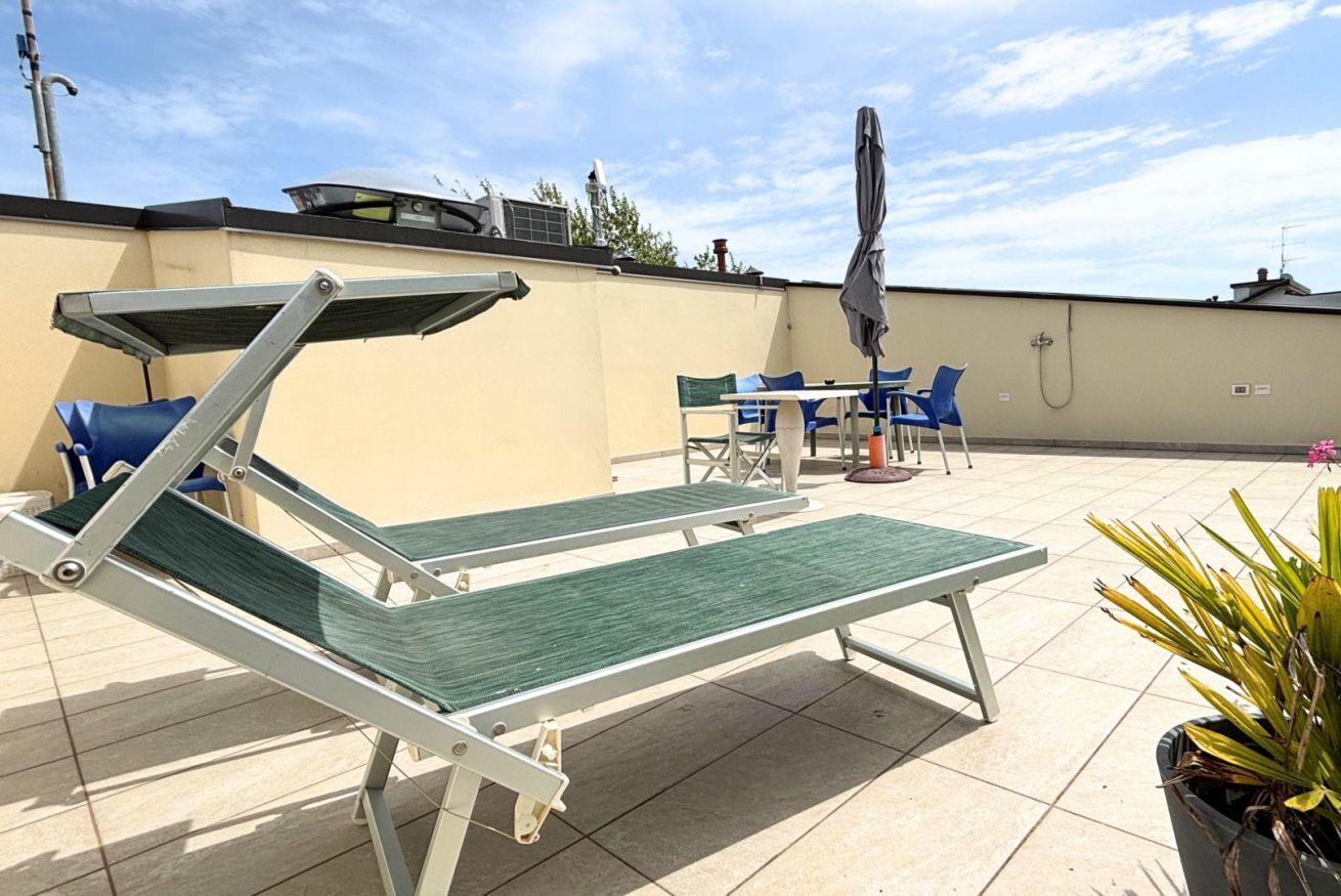 A rooftop terrace with a pool table, lounge chairs, and a table with chairs.