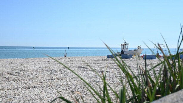 Une plage avec un bateau et une petite construction sur le rivage, qui ressemble probablement à un poste de surveillance des sauveteurs.