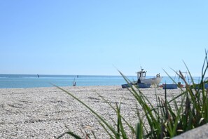 A beach with a boat and a small structure, likely a lifeguard station, on the shore.