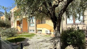Une cour avec un arbre, une zone recouverte de gravier et des bâtiments dotés de balcons et de fenêtres.