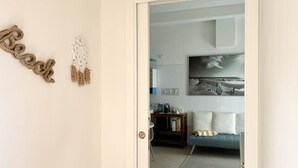Une porte qui donne sur un salon, où l’on trouve un canapé, une table basse et un tableau accroché au mur.
